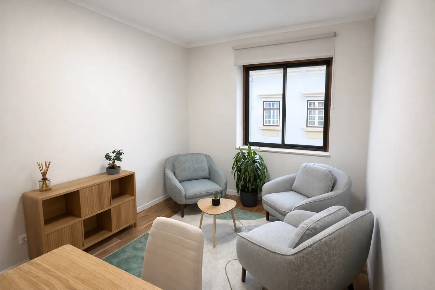 Vista geral da sala, com estante baixa e zona de conversa